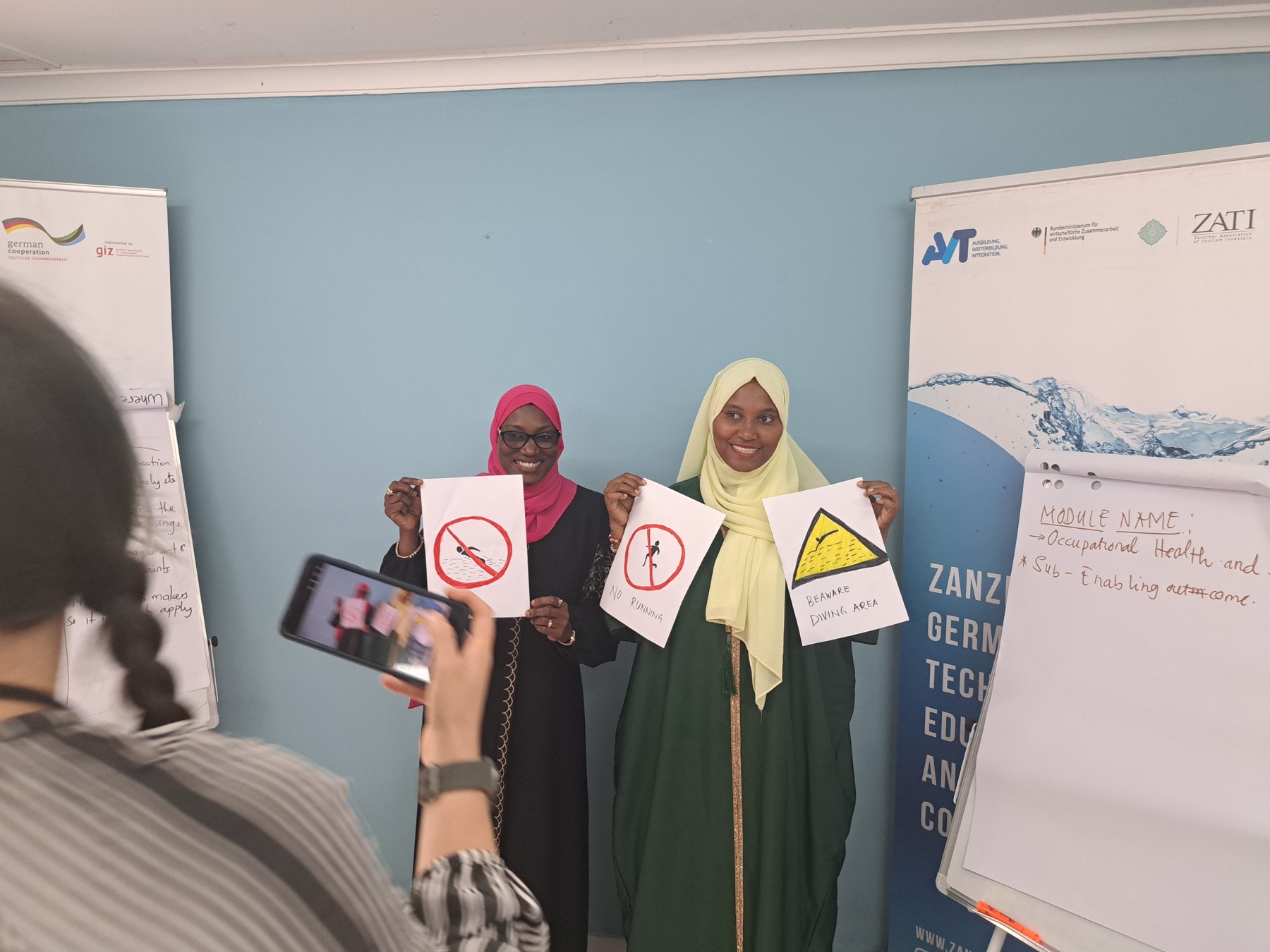 Two women presenting occupational safety signs during training